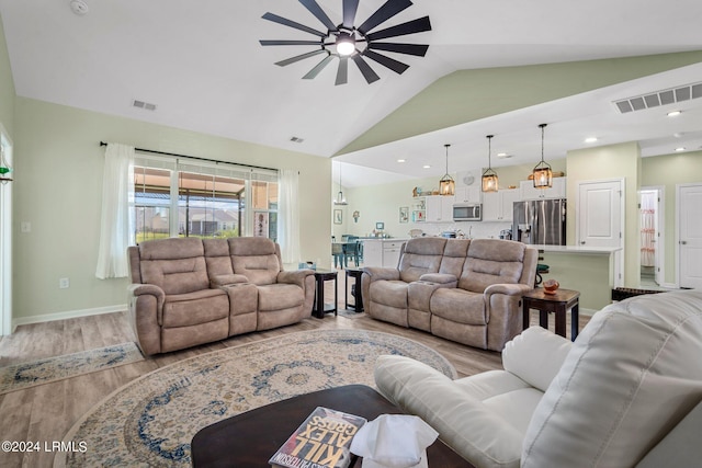 living room with vaulted ceiling, ceiling fan, and light wood-type flooring