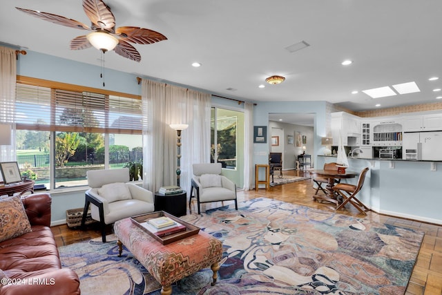 living room featuring ceiling fan and a skylight