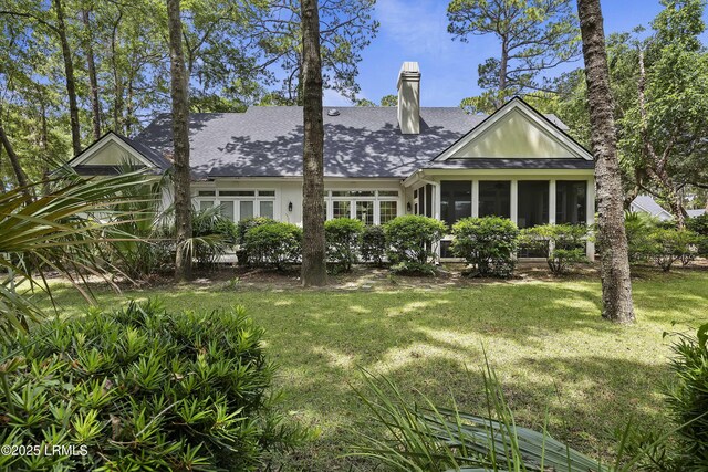 2 Lenox Ln, Hilton Head Island, SC 29926 - back of house featuring roof with shingles, a chimney, a yard, and a sunroom