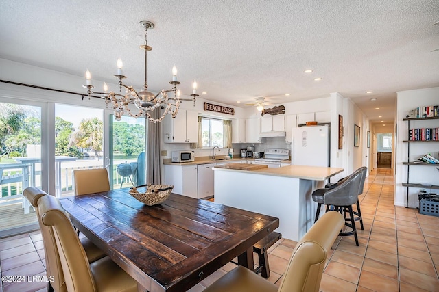 dining area with ceiling fan with notable chandelier, sink, light tile patterned floors, and a textured ceiling