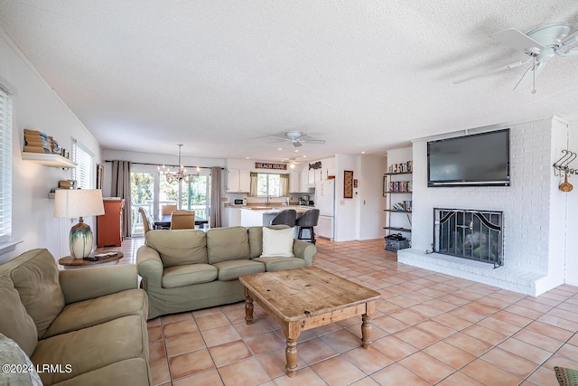 tiled living room featuring plenty of natural light, a brick fireplace, ceiling fan with notable chandelier, and a textured ceiling