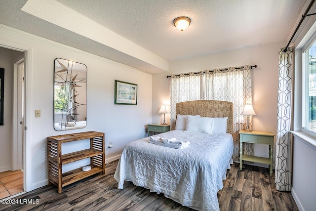 bedroom featuring multiple windows, a textured ceiling, and dark hardwood / wood-style flooring