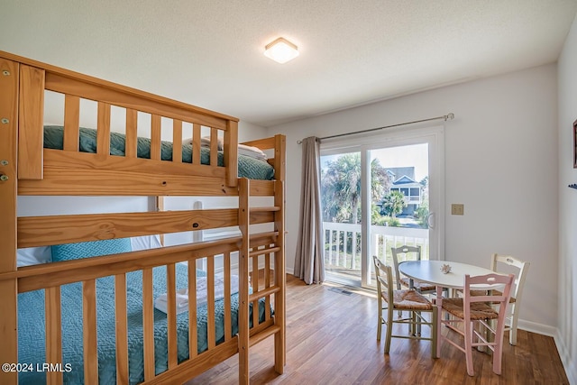 bedroom with hardwood / wood-style flooring, access to exterior, and a textured ceiling