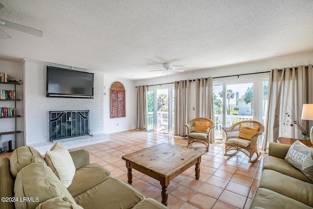 tiled living room with ceiling fan, a textured ceiling, and a fireplace