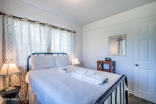 bedroom with a textured ceiling and dark hardwood / wood-style flooring