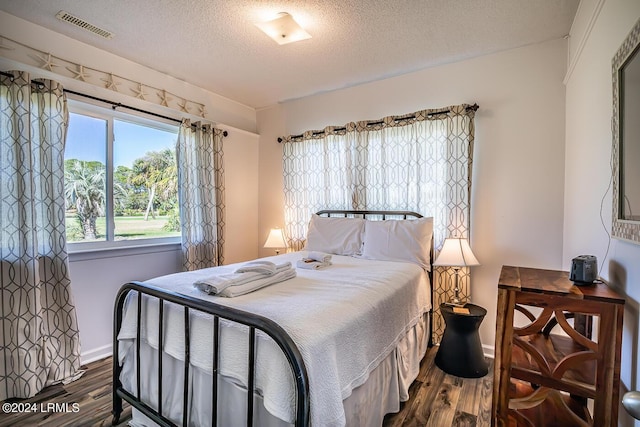 bedroom with dark hardwood / wood-style floors and a textured ceiling