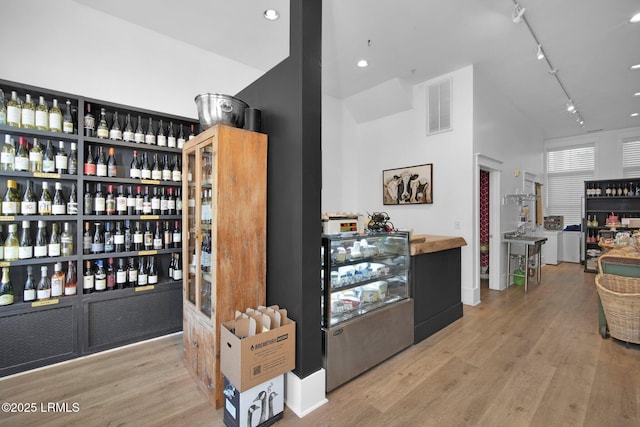 wine area with light hardwood / wood-style flooring, rail lighting, and bar area