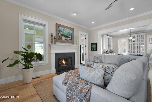 living room with ornamental molding, sink, a wealth of natural light, and light wood-type flooring