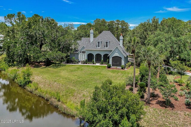 4 Wedgewood Cir, Bluffton, SC 29910 - view of front of house with stucco siding, a front lawn, a chimney, a water view, and view of scattered trees
