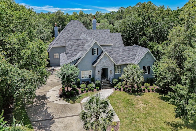 4 Wedgewood Cir, Bluffton, SC 29910 - french country style house with stone siding, a chimney, a front yard, and roof with shingles