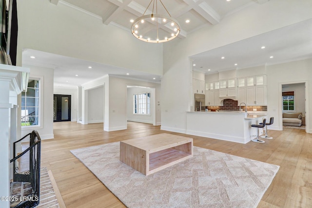 4 Wedgewood Cir, Bluffton, SC 29910 - living room with a towering ceiling, light wood finished floors, beamed ceiling, a chandelier, and crown molding