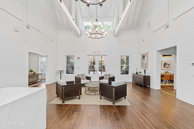 living room with a high ceiling, wood-type flooring, a notable chandelier, and french doors