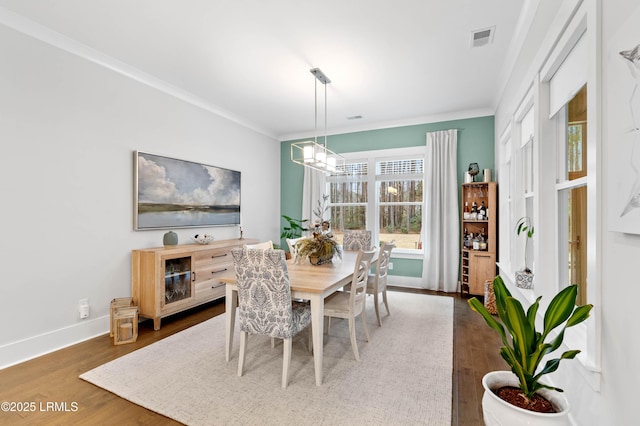 dining area with an inviting chandelier, ornamental molding, and dark hardwood / wood-style flooring