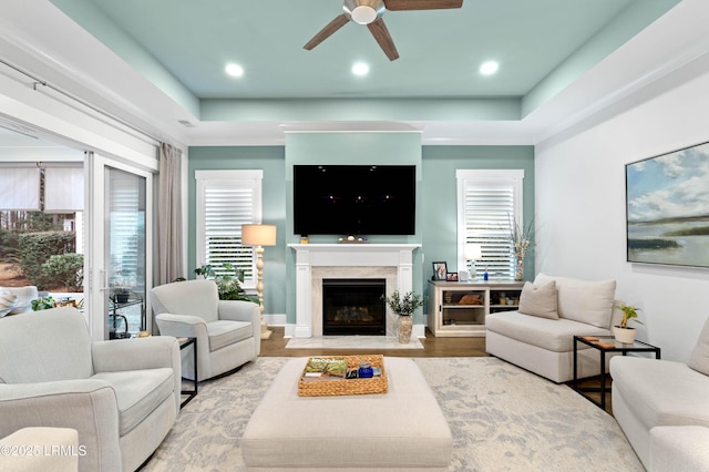 living room with a tray ceiling and ceiling fan