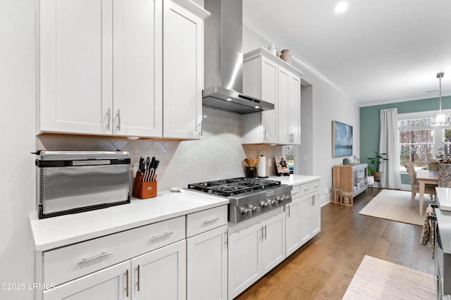 kitchen featuring crown molding, white cabinetry, hanging light fixtures, stainless steel gas cooktop, and wall chimney exhaust hood