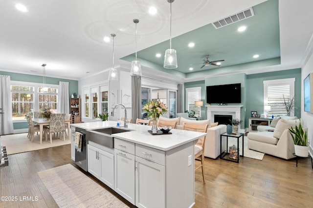 kitchen featuring white cabinetry, sink, a kitchen island with sink, and hanging light fixtures