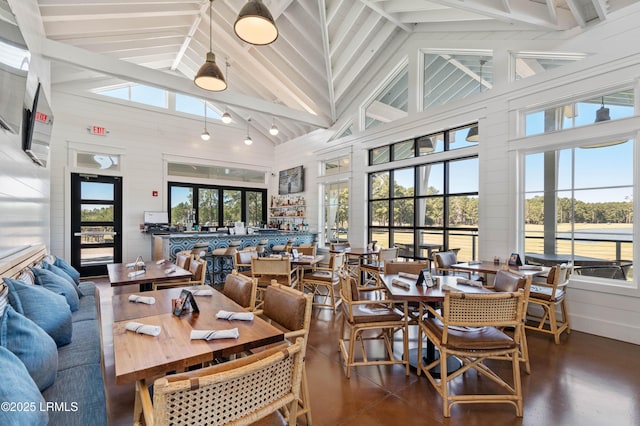 dining space featuring wooden walls, high vaulted ceiling, and beamed ceiling