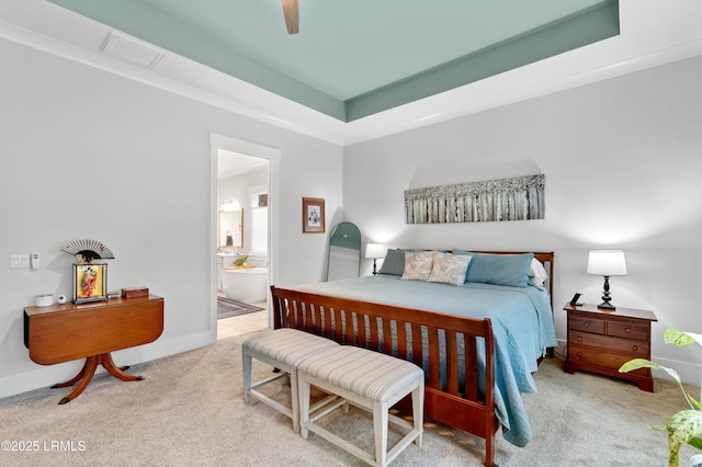 carpeted bedroom with a tray ceiling, ensuite bath, and ceiling fan