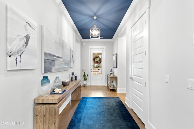 doorway featuring ornamental molding, hardwood / wood-style floors, and a notable chandelier