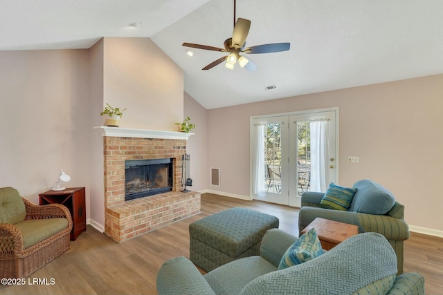 living room with light hardwood / wood-style floors, high vaulted ceiling, ceiling fan, and a fireplace