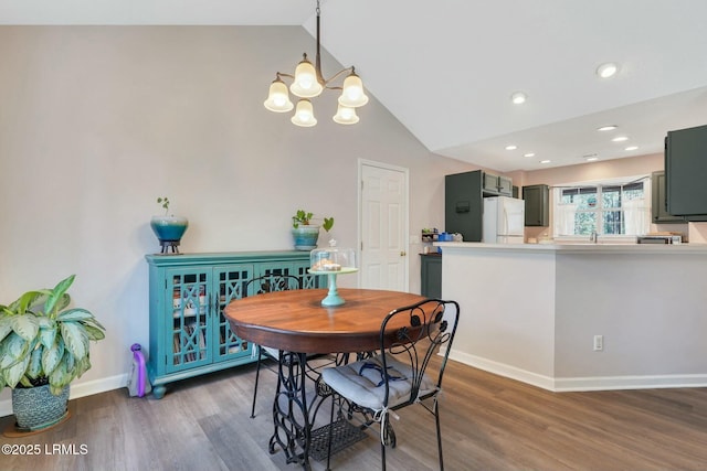 dining area featuring a chandelier, vaulted ceiling, and dark hardwood / wood-style floors