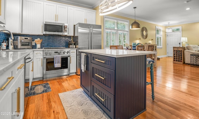 8 Battery Point Ln, Beaufort, SC 29902 - kitchen featuring stainless steel appliances, white cabinets, crown molding, a kitchen breakfast bar, and backsplash