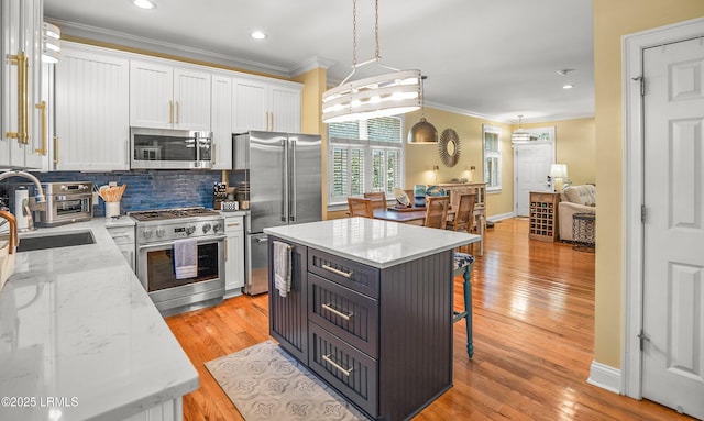 8 Battery Point Ln, Beaufort, SC 29902 - kitchen featuring high quality appliances, crown molding, a breakfast bar area, white cabinetry, and backsplash