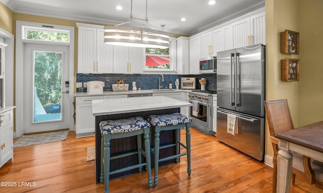 8 Battery Point Ln, Beaufort, SC 29902 - kitchen with high end appliances, ornamental molding, tasteful backsplash, white cabinets, and a breakfast bar