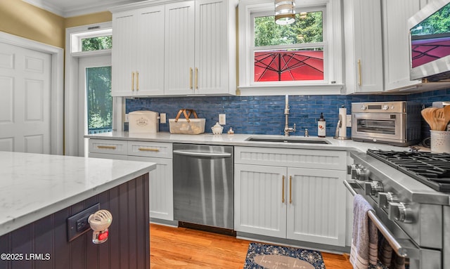 8 Battery Point Ln, Beaufort, SC 29902 - kitchen with stainless steel appliances, backsplash, light wood-style flooring, crown molding, and white cabinetry