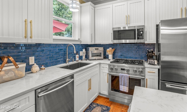 8 Battery Point Ln, Beaufort, SC 29902 - kitchen with stainless steel appliances, white cabinetry, backsplash, light wood finished floors, and light stone countertops