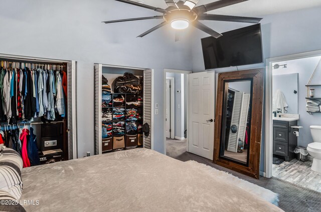 carpeted bedroom featuring sink, ensuite bath, ceiling fan, and a high ceiling