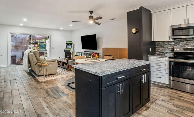 kitchen featuring stainless steel appliances, tasteful backsplash, a kitchen island, and white cabinets