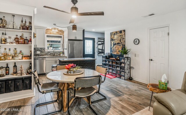 dining room with indoor wet bar, light hardwood / wood-style floors, and ceiling fan