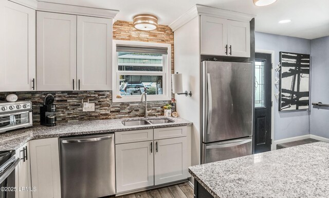 kitchen featuring appliances with stainless steel finishes, tasteful backsplash, sink, white cabinets, and light stone counters