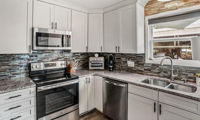 kitchen featuring stone counters, appliances with stainless steel finishes, white cabinetry, sink, and decorative backsplash