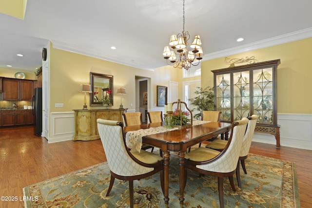 19 Lynnfield Pl, Bluffton, SC 29910 - dining area with a chandelier, dark wood finished floors, crown molding, a wainscoted wall, and recessed lighting