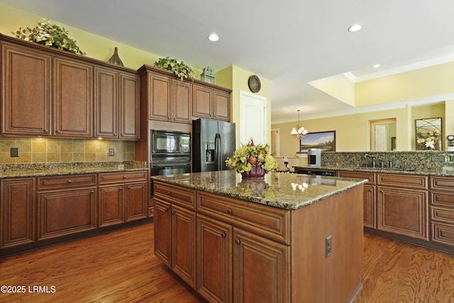 19 Lynnfield Pl, Bluffton, SC 29910 - kitchen with black appliances, a kitchen island, dark wood-style floors, ornamental molding, and dark stone counters