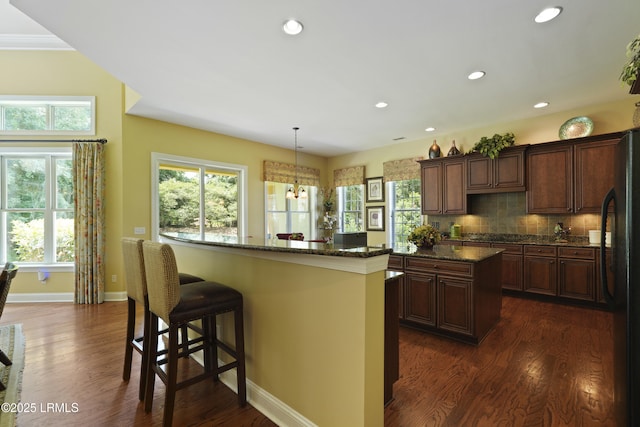 19 Lynnfield Pl, Bluffton, SC 29910 - kitchen with a center island, freestanding refrigerator, dark wood-type flooring, a breakfast bar, and dark stone countertops