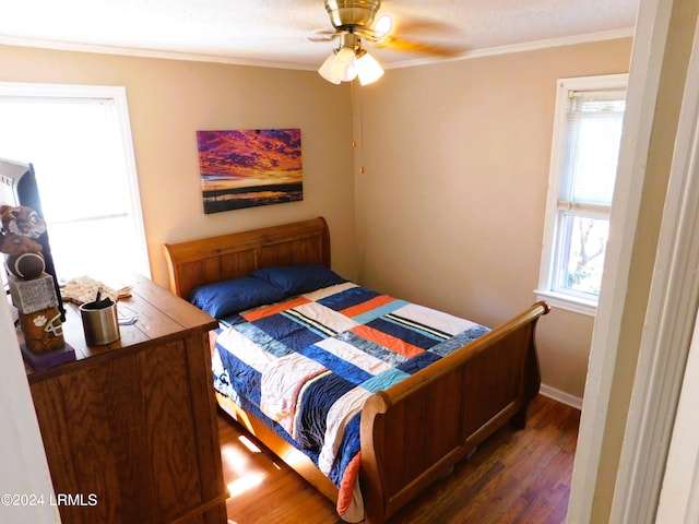 bedroom featuring multiple windows, dark hardwood / wood-style flooring, crown molding, and ceiling fan