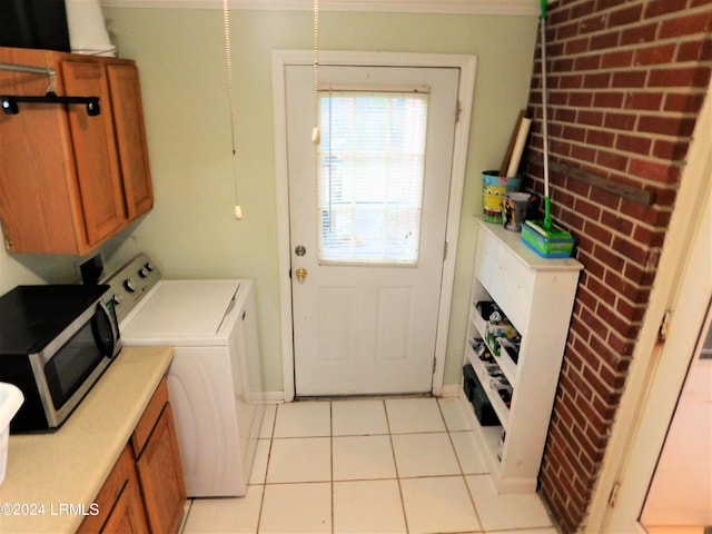 laundry room with crown molding, washer and dryer, and light tile patterned floors