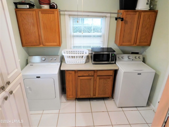 laundry area with cabinets, washer / dryer, and light tile patterned floors