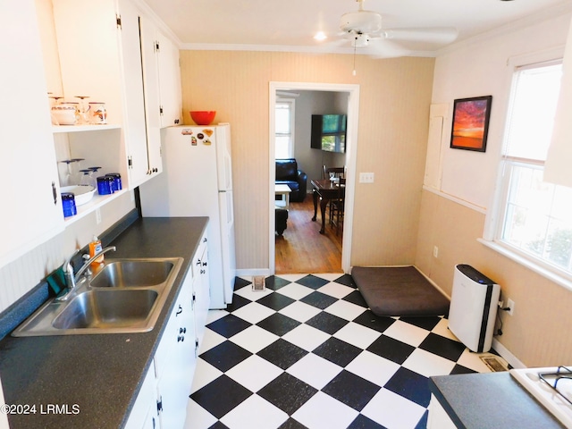 kitchen featuring white refrigerator, ornamental molding, sink, and white cabinets