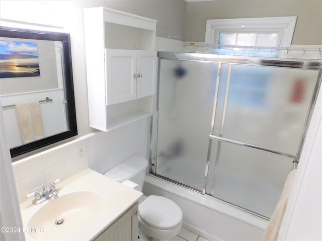 full bathroom featuring tasteful backsplash, bath / shower combo with glass door, vanity, and toilet