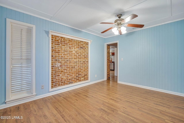 spare room with ceiling fan, brick wall, ornamental molding, and light hardwood / wood-style floors