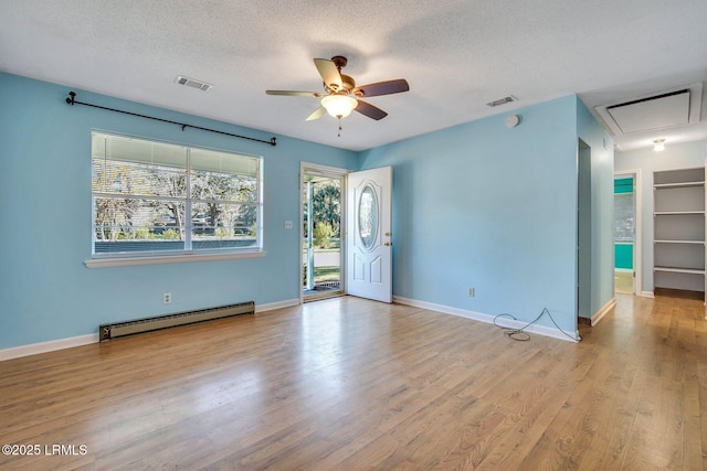 spare room featuring a baseboard radiator, light hardwood / wood-style floors, a textured ceiling, and plenty of natural light