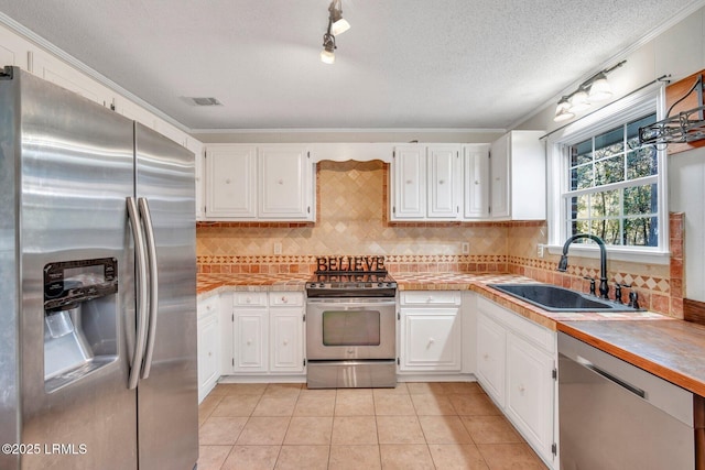 kitchen with white cabinetry, stainless steel appliances, sink, and light tile patterned floors