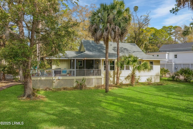 view of front of property with a front lawn, a sunroom, a deck, and a shingled roof