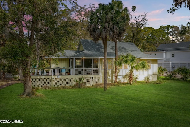 back of house with a lawn, a sunroom, and a wooden deck