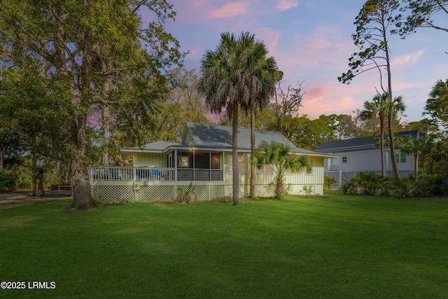 back of property at dusk featuring a lawn