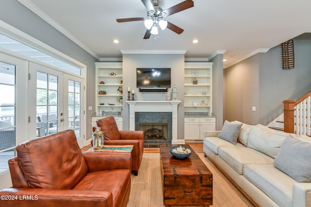 living room with ceiling fan, ornamental molding, a tiled fireplace, and light hardwood / wood-style flooring